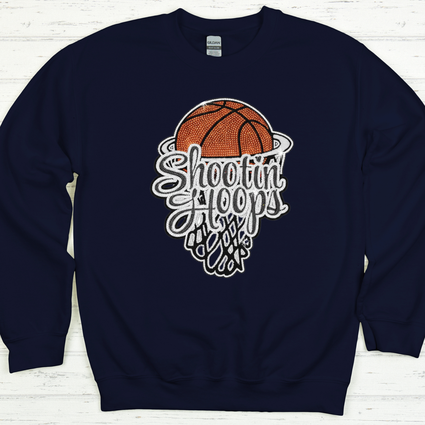 Navy blue sweatshirt with a basketball graphic and text on a white wooden background
