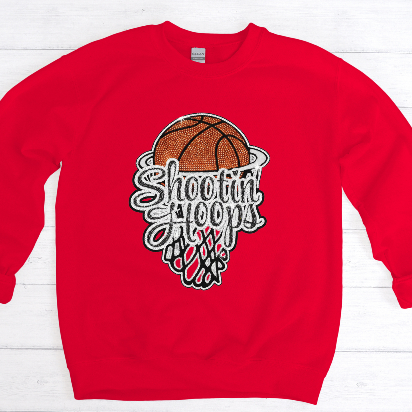 Red sweatshirt with a basketball graphic and 'Shootin' Hoops' text on a white wooden background