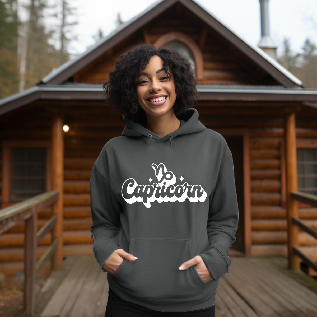 A woman wearing a dark gray hoodie with a white 'Capricorn' graphic on the chest, sitting on a couch.