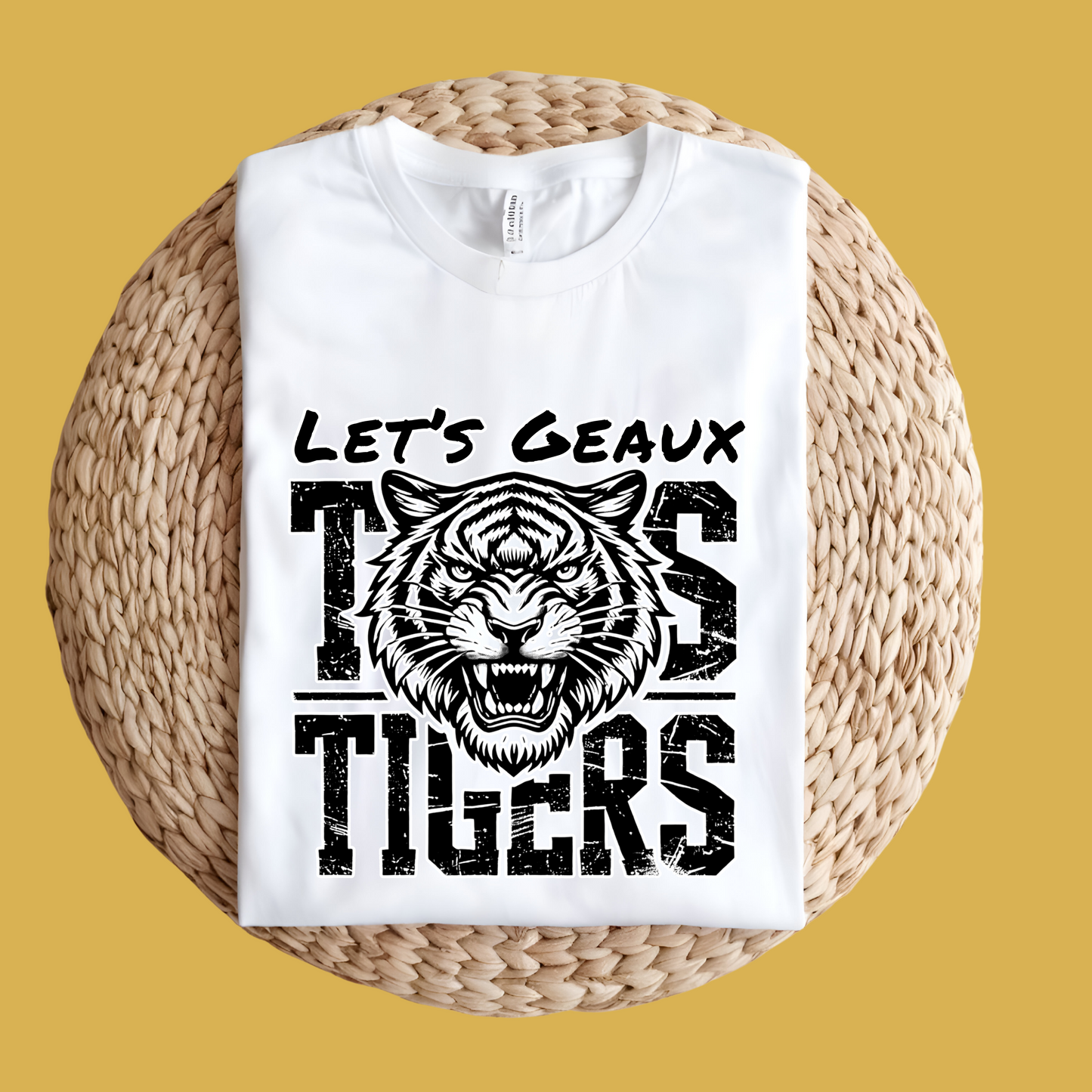 White t-shirt with tiger graphic and text 'Let's Geaux Tigers' on a woven surface with yellow background Let's Geaux Tigers T-Shirt - Fierce Tiger Graphic Game Day Tee