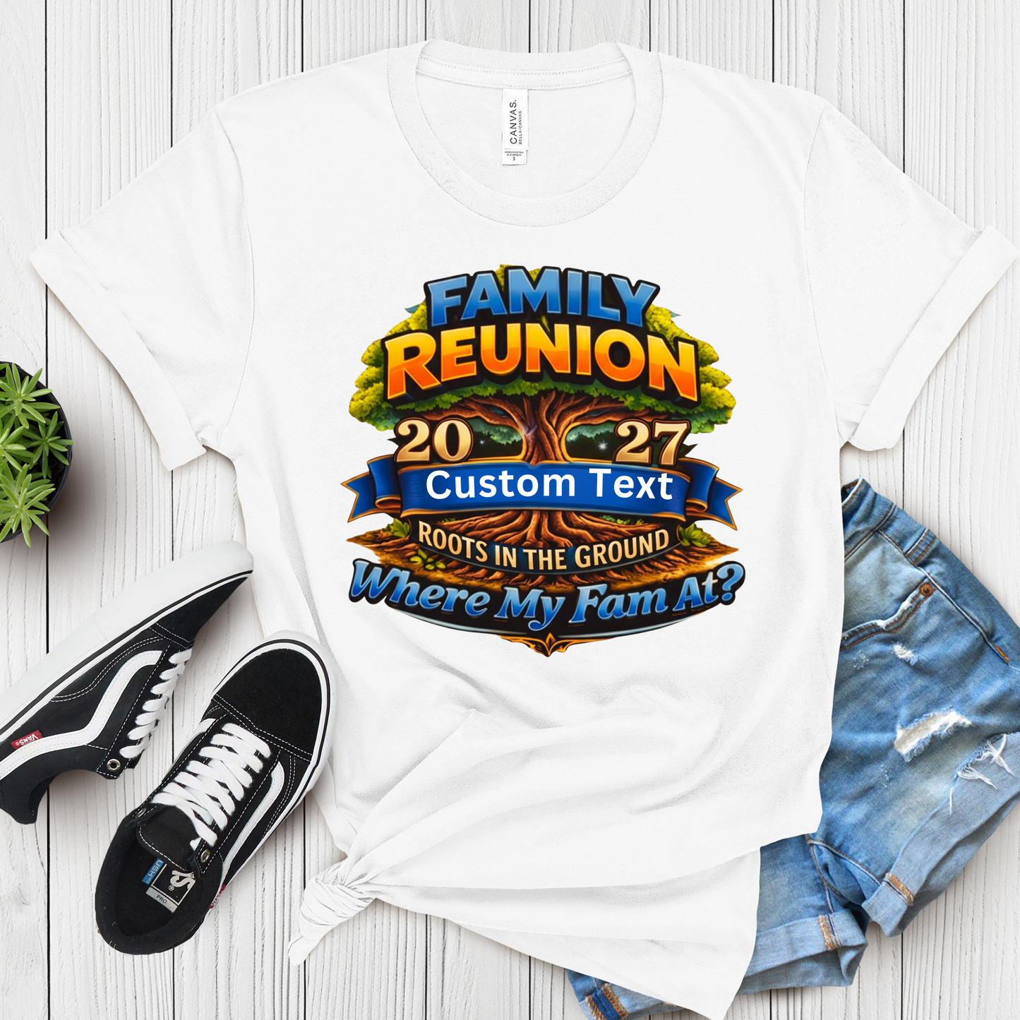 White t-shirt with family reunion design on a wooden surface with shoes and jeans.