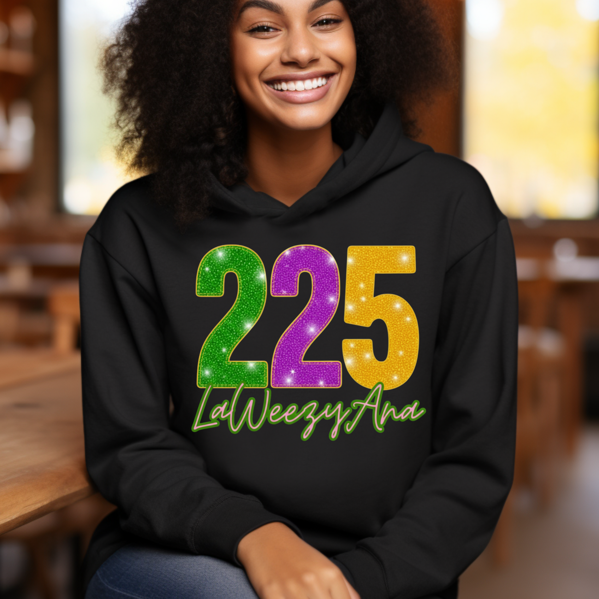 Person wearing a black hoodie with colorful numbers and text, sitting indoors.