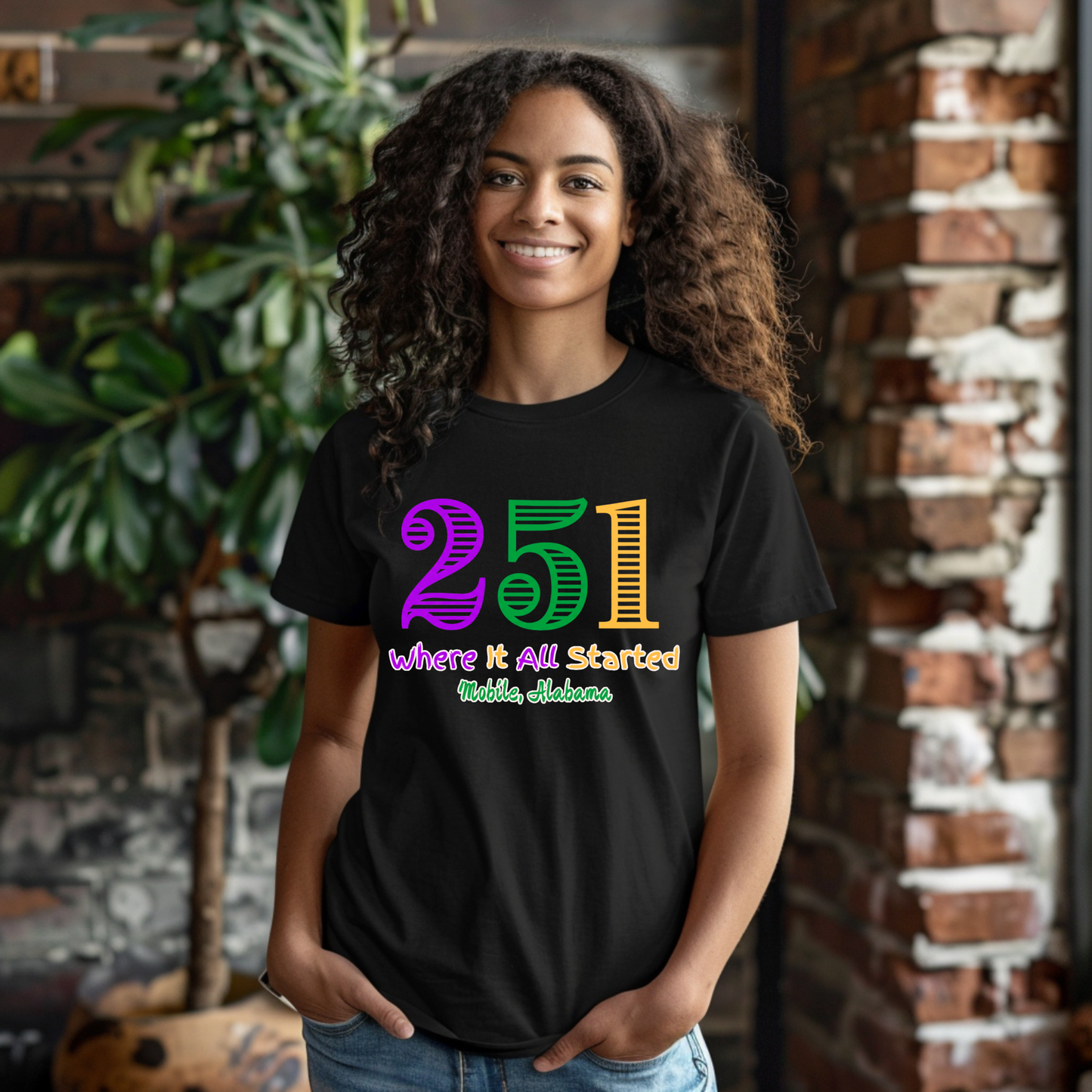 Person wearing a black t-shirt with colorful text standing in front of a brick wall.