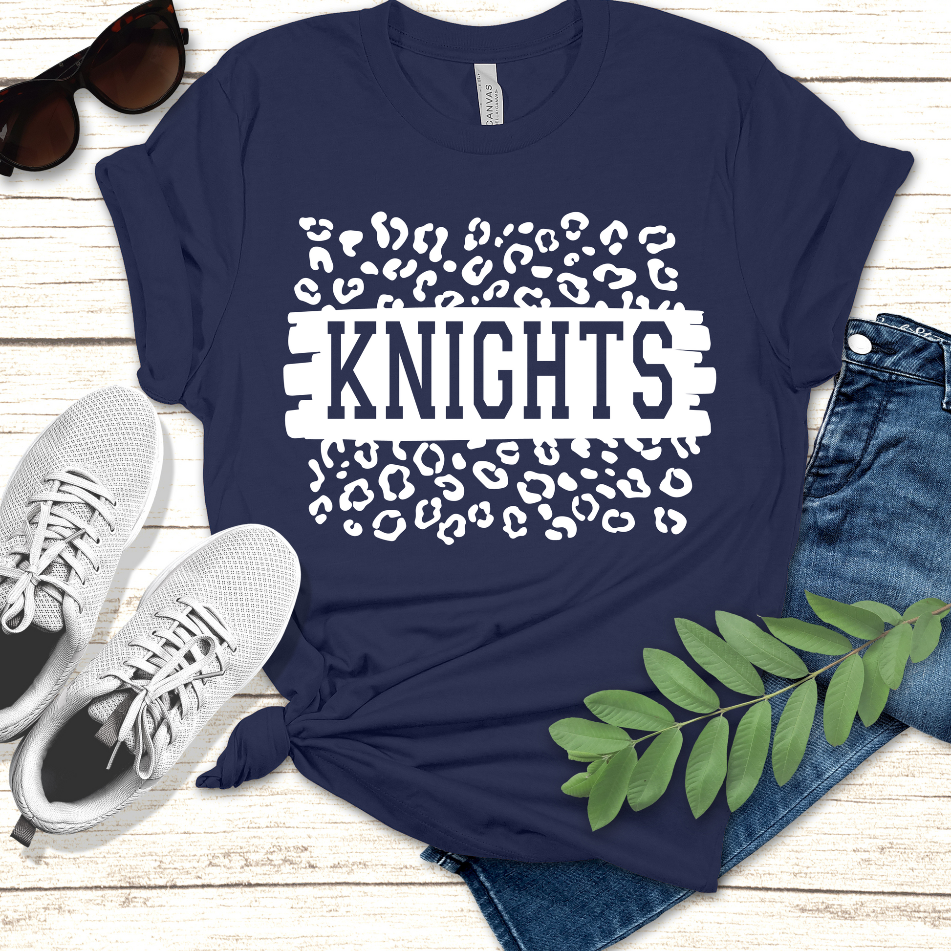 Navy blue t-shirt with 'KNIGHTS' design on a wooden surface with shoes and jeans. Knights School Spirit Shirt - Knights Leopard - School Pride Graphic T-Shirt
