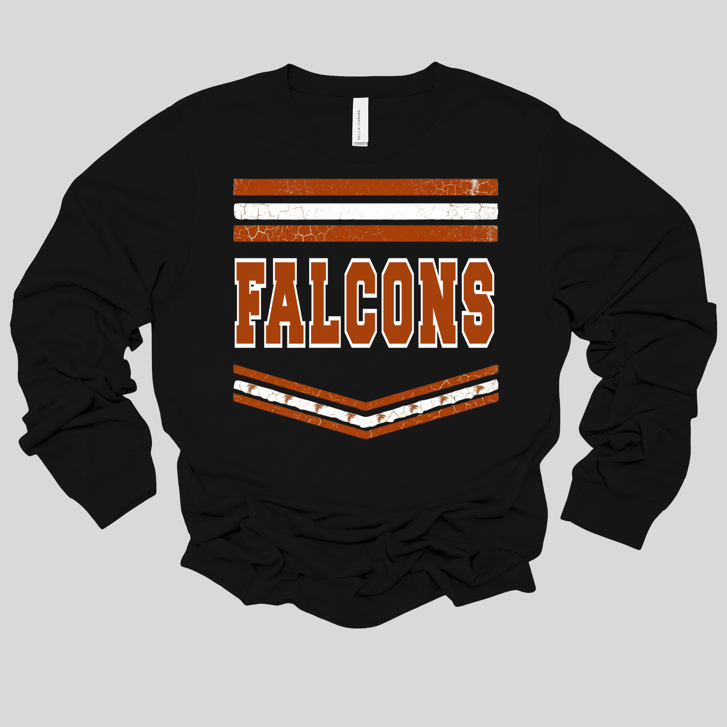 A black long-sleeve t-shirt with a distressed orange and white graphic on the chest that reads 'FALCONS' with horizontal stripes above and below, displayed on a solid gray background.