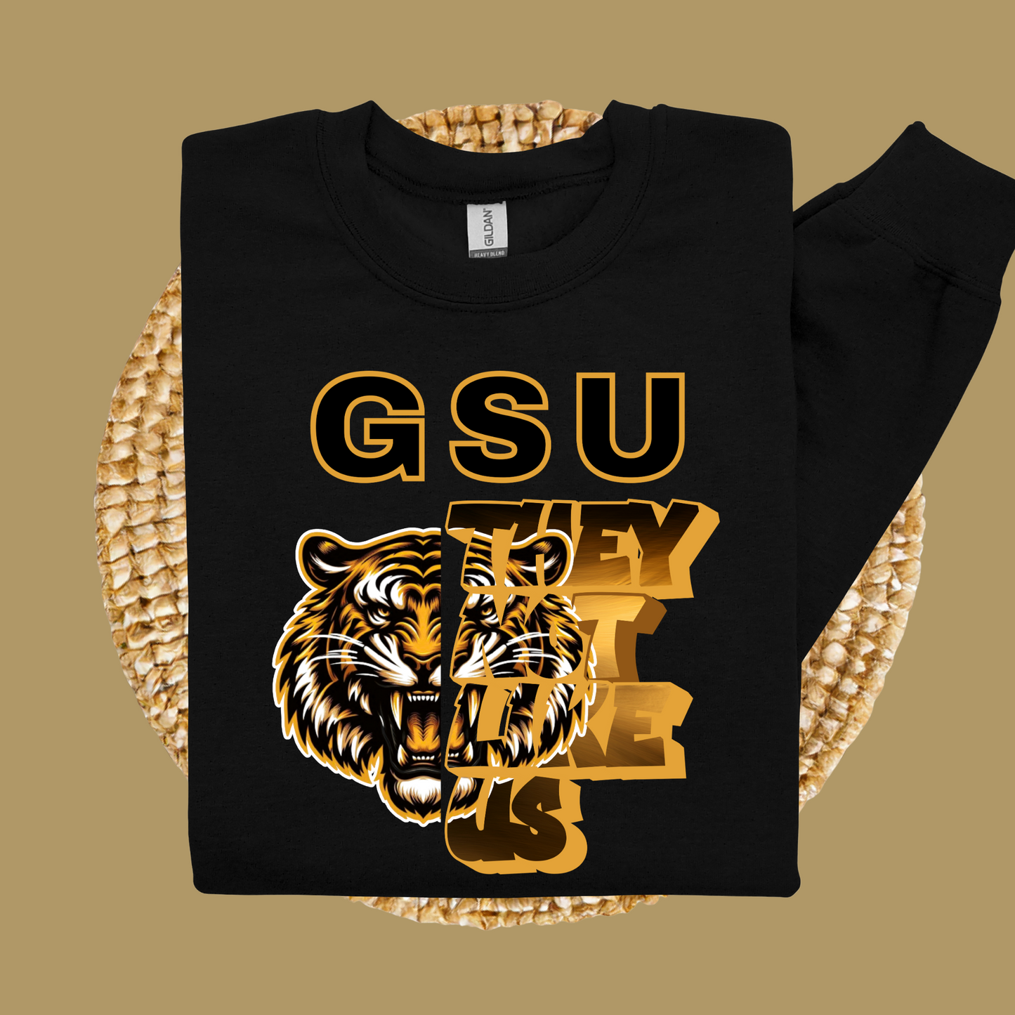 Black sweatshirt with gold 'GSU THEY LIKE US' text and tiger graphic on a woven surface. Grambling Football:  GSU They Not Like Us Game Day Unisex Crewneck Sweatshirt
