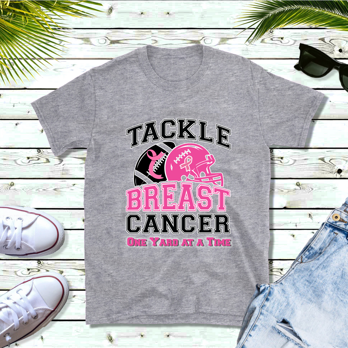 Gray t-shirt with 'Tackle Breast Cancer One Yard at a Time' design on a wooden surface with sneakers and shorts. October Awareness Shirt - Tackle for a Cause One Yard at a Time Tee