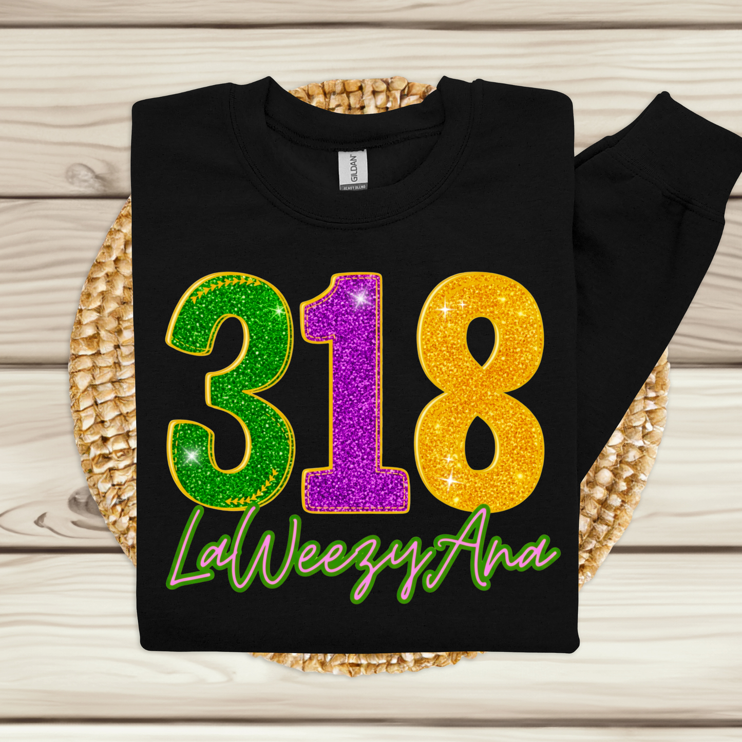 Black sweatshirt with colorful numbers '318' and text 'LaWeezyAna' on a wooden surface.
