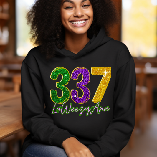 Person wearing a black hoodie with colorful numbers and text, sitting indoors.