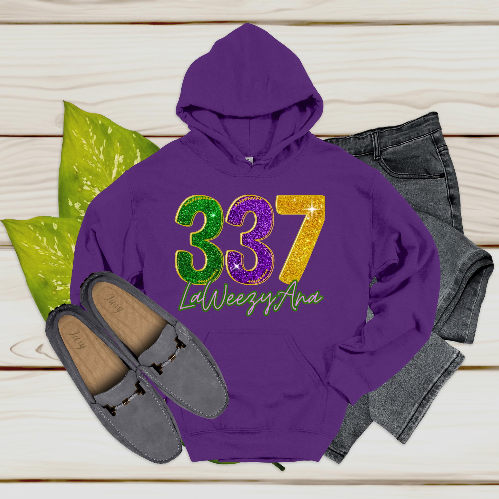 Purple hoodie with '337 LaWeezyAna' text, paired with jeans and loafers on a wooden surface.