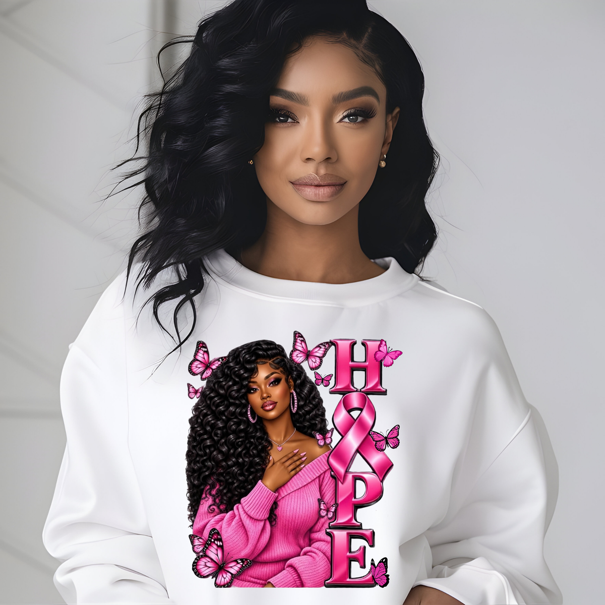 A woman wearing a white crewneck sweatshirt with a graphic print featuring a Black woman in a pink sweater, pink butterflies, and the word 'HOPE' in pink letters with a pink ribbon.