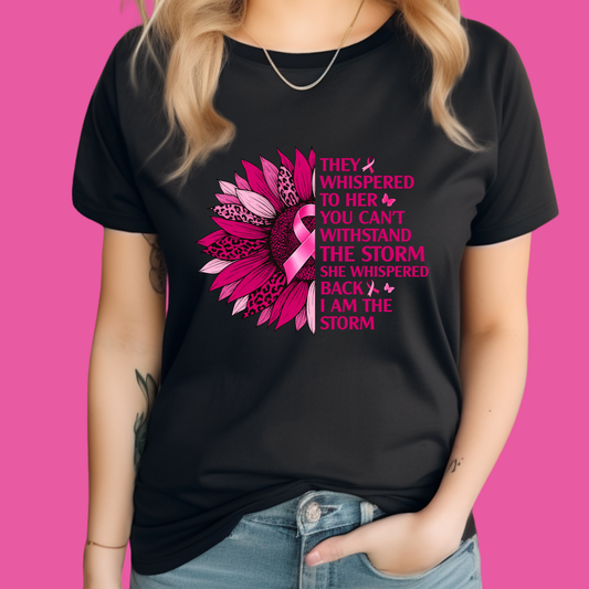 Person wearing a black t-shirt with a pink ribbon design and motivational text on a pink background  Pink Ribbon Tee: I AM THE STORM Breast Cancer Awareness Powerful Tee