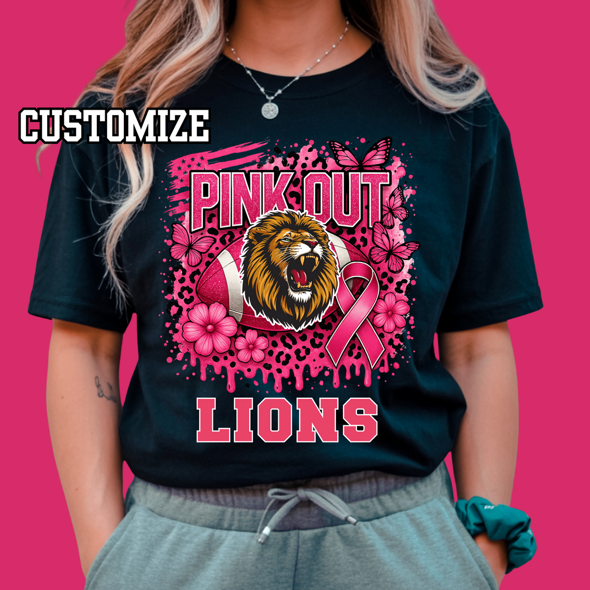 Person wearing a black t-shirt with 'Pink Out Lions' design featuring a lion, football, and pink ribbon on a pink background.