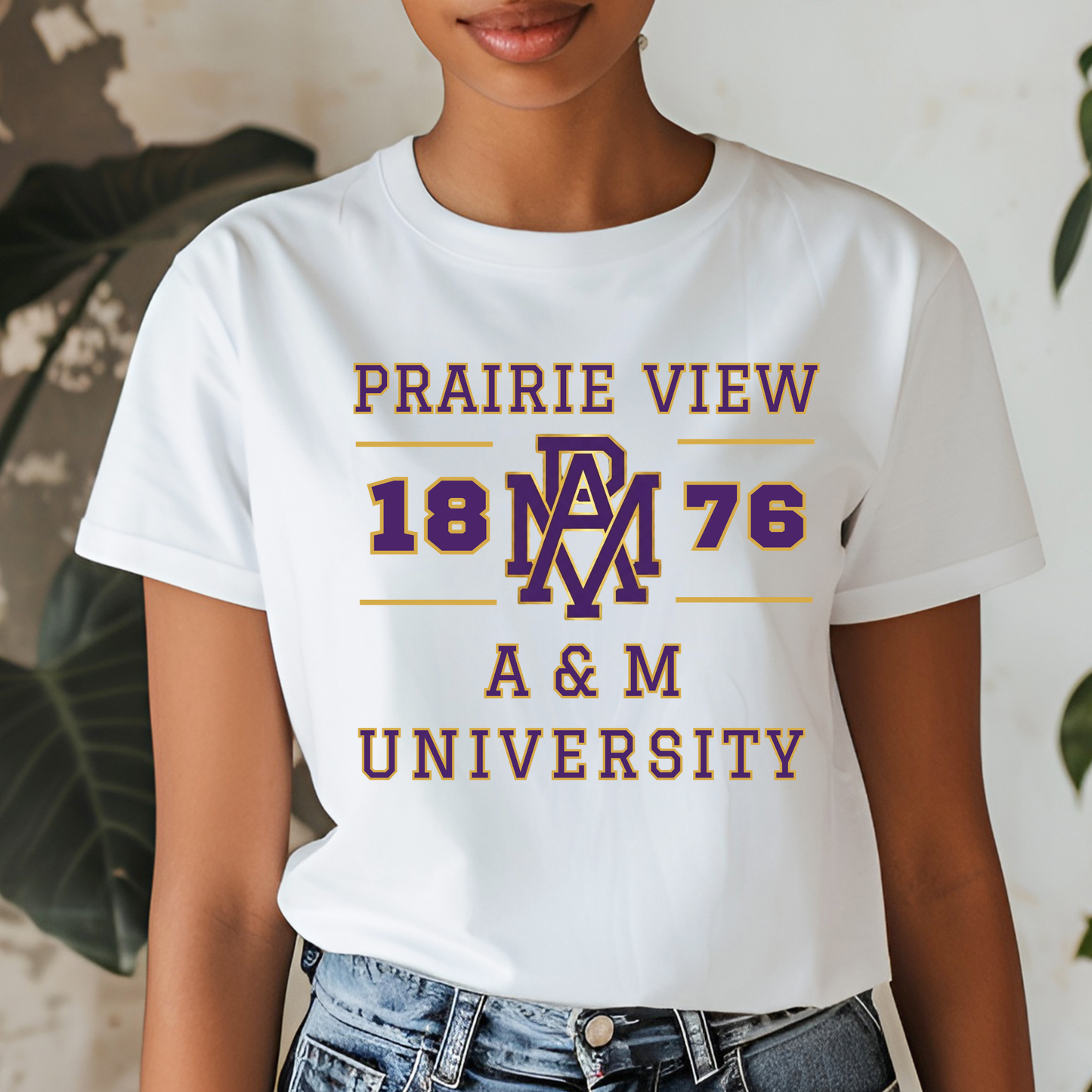 A woman wearing a white graphic t-shirt with 'PRAIRIE VIEW 1876 A & M UNIVERSITY' printed in maroon and gold, paired with blue jeans.