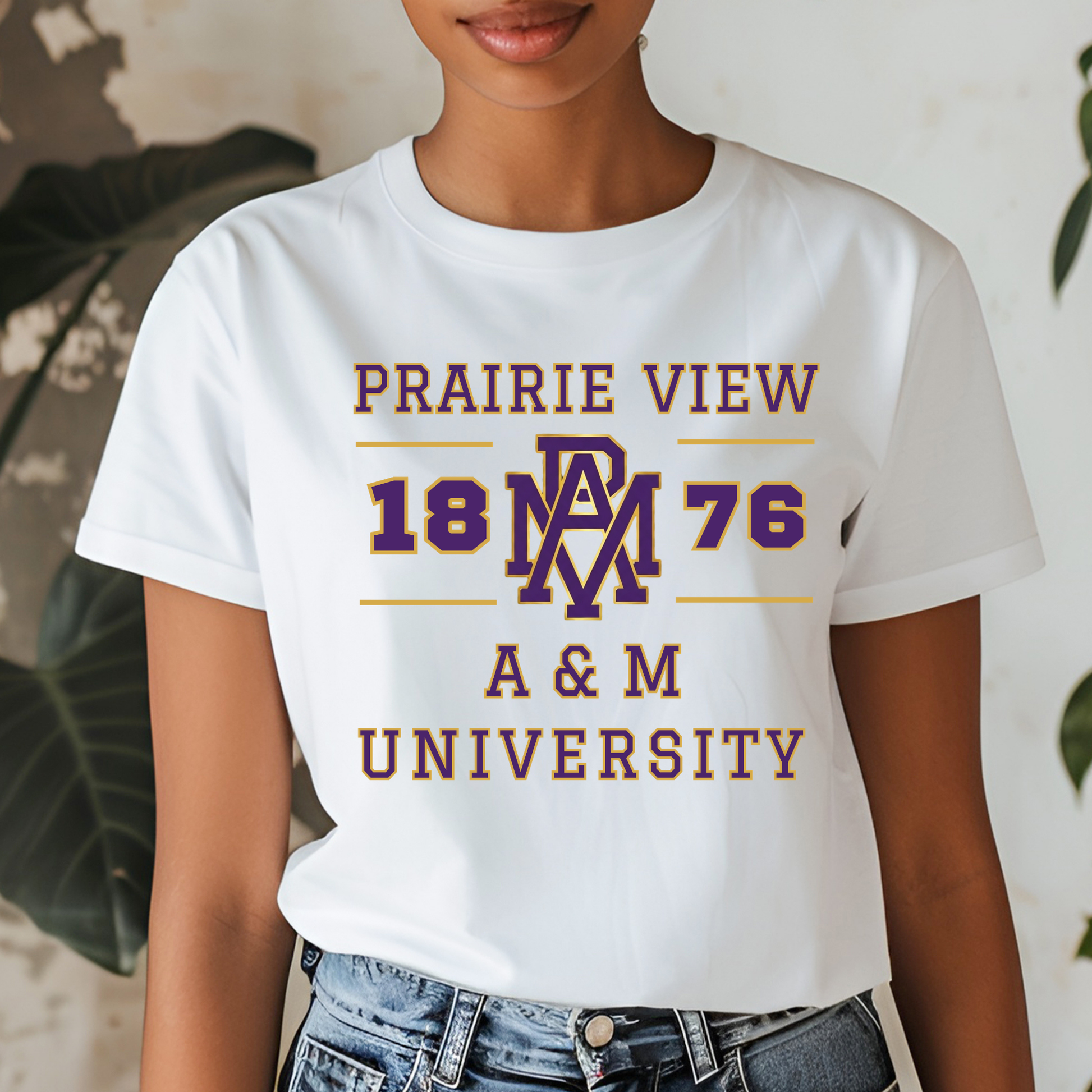A woman wearing a white graphic t-shirt with 'PRAIRIE VIEW 1876 A & M UNIVERSITY' printed in maroon and gold, paired with blue jeans.