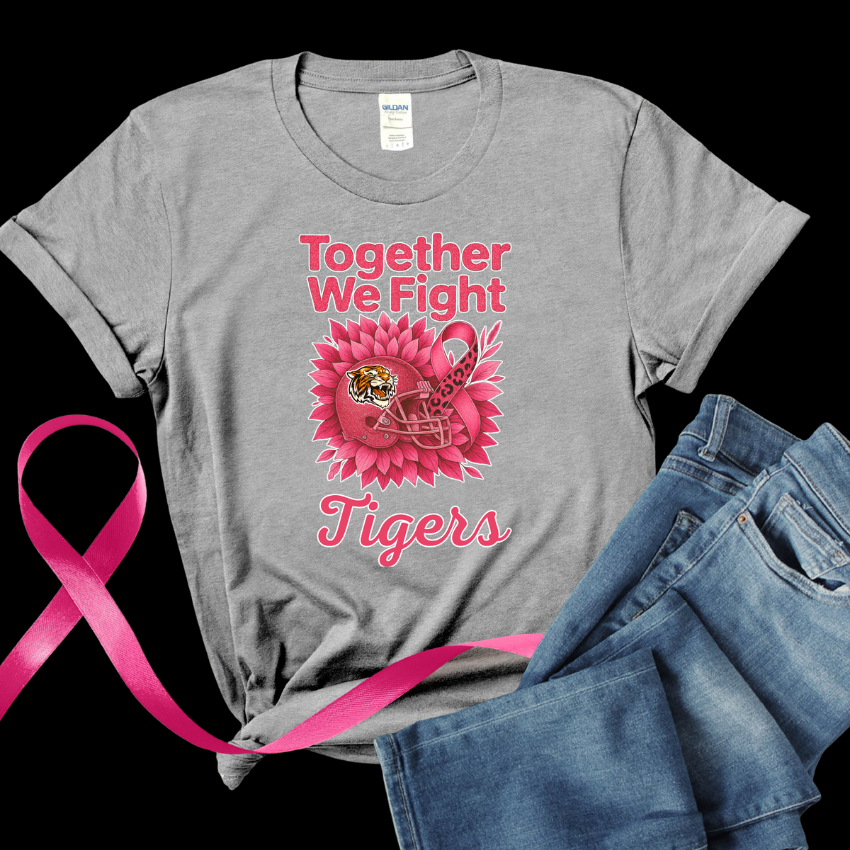 Gray t-shirt with pink ribbon and 'Tigers' design, next to a pink ribbon and jeans on a black background