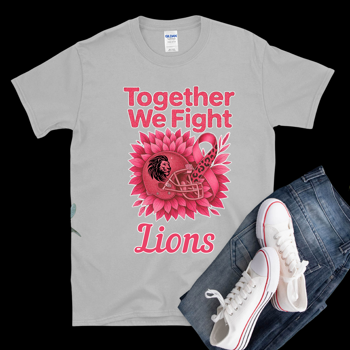 Gray t-shirt with pink lion design and text, paired with jeans and white sneakers on a black background.
