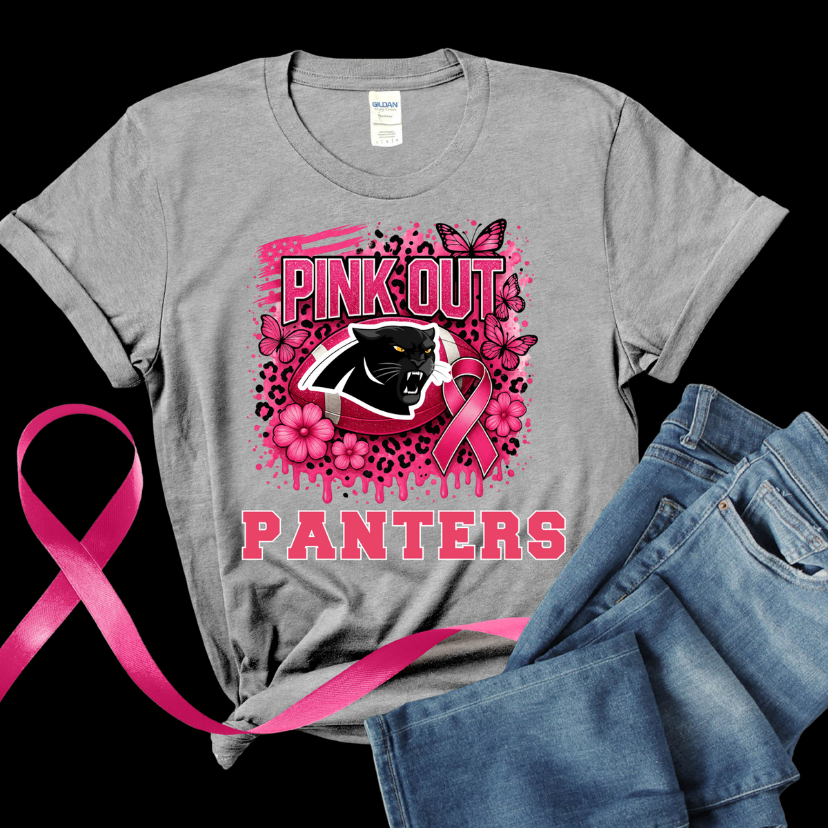 Gray t-shirt with pink 'Pink Out Panthers' design featuring a panther logo and pink ribbon, next to a pink ribbon and blue jeans on a black background.