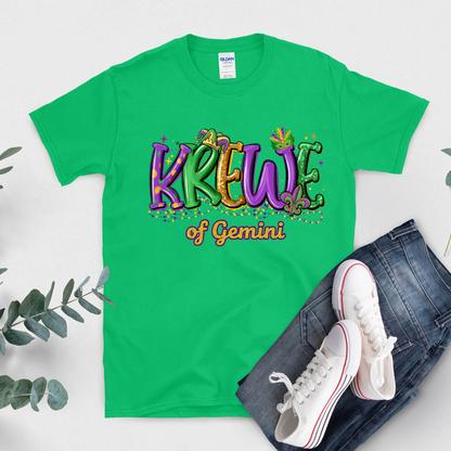 Green t-shirt with 'Krew of Gemini' design, white sneakers, and jeans on a light gray background