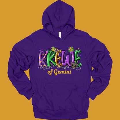 Purple hoodie with 'Krewe of Gemini' text on a mustard yellow background