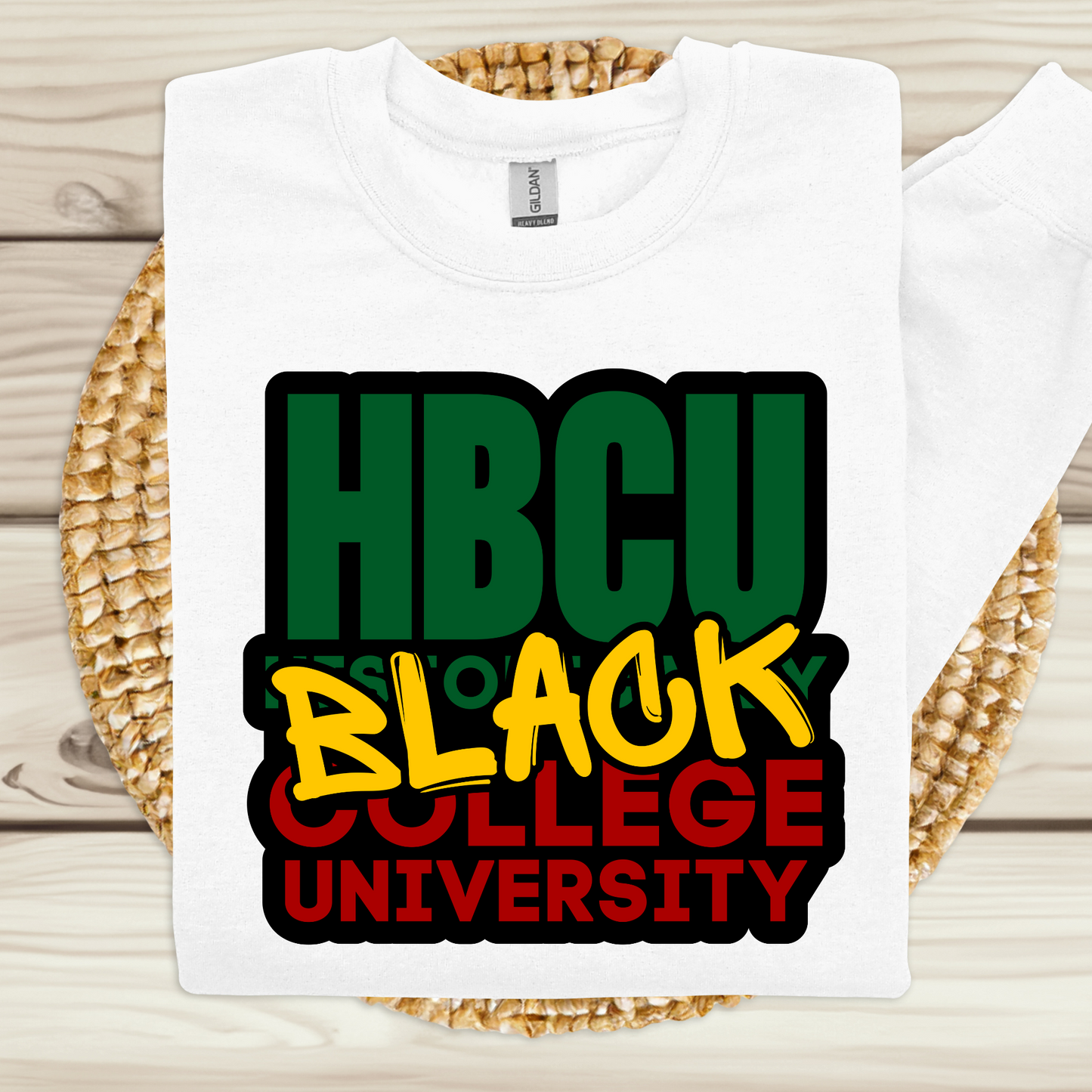 White t-shirt with 'HBCU Black College University' text in green, yellow, and red on a woven mat.