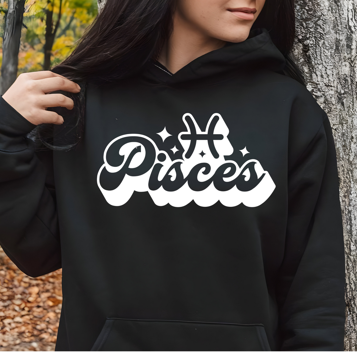 A person wearing a black pullover hoodie with a large white and black 'My Virgo' graphic on the chest, standing outdoors next to a tree trunk.