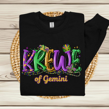 Black sweatshirt with colorful 'KREWE of Gemini' text on a wooden surface