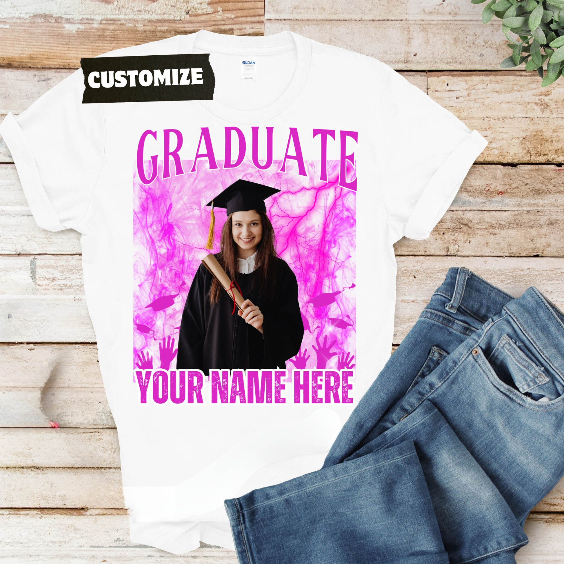 Graduation-themed t-shirt with customizable text on a wooden surface with jeans.  Customizable graduation photo t-shirt featuring senior portrait, school mascot, and sports organization logos in school colors