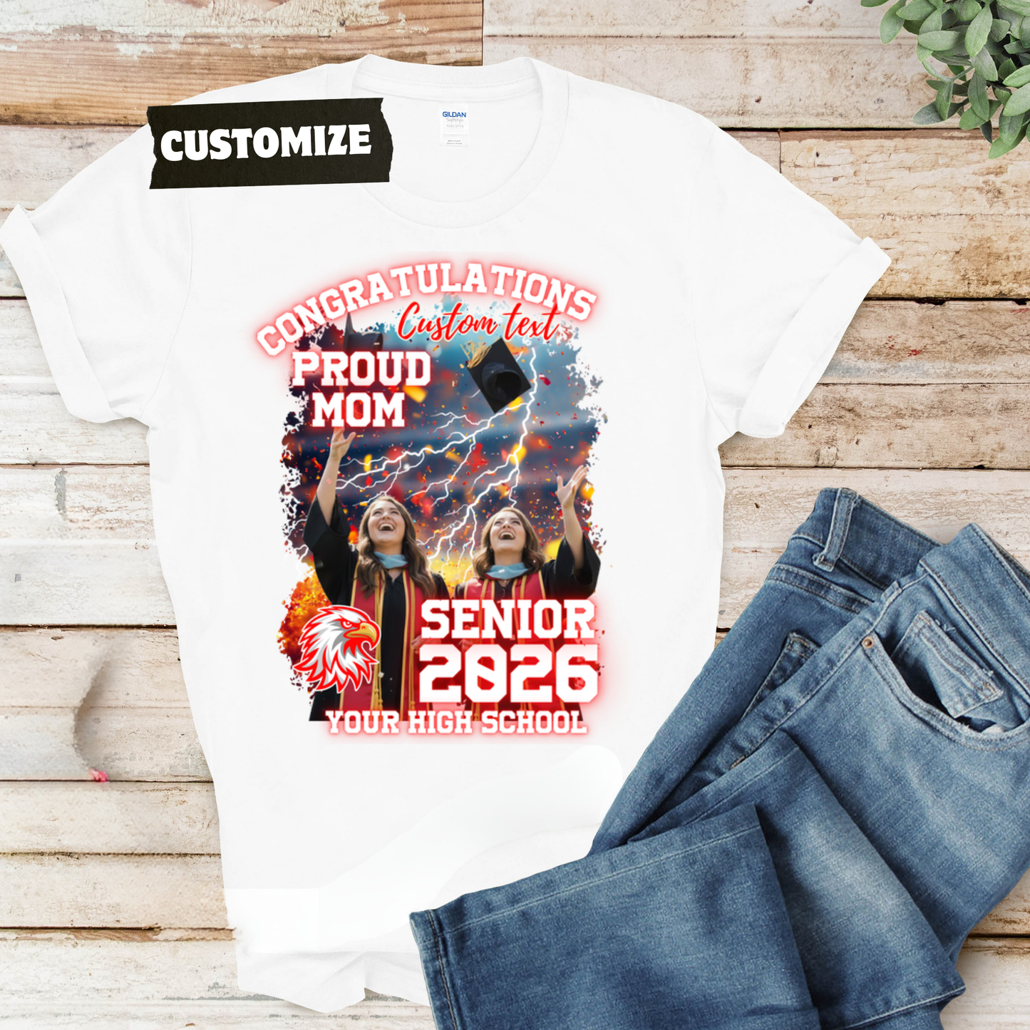 White t-shirt with graduation design and jeans on a wooden surface  Customizable graduation photo t-shirt featuring senior portrait, school mascot, and sports organization logos in school colors