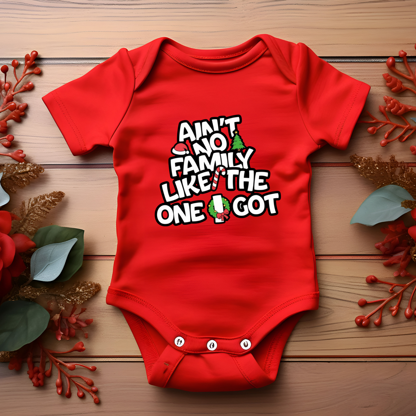 Red baby onesie with text on a wooden surface with decorative elements