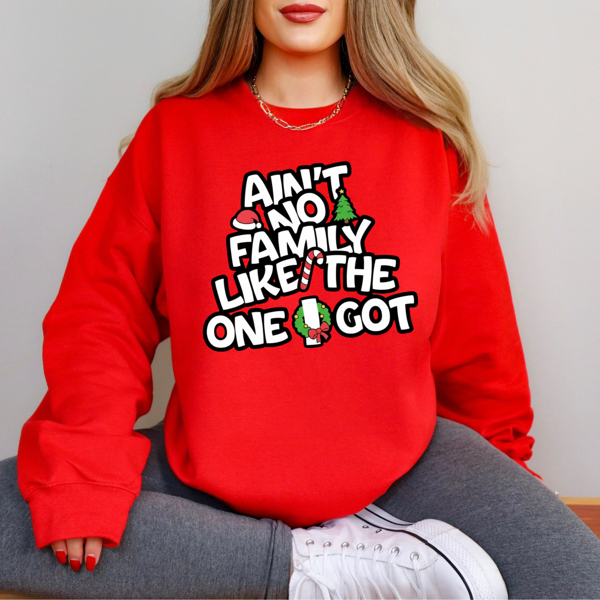 Red sweatshirt with humorous text design worn by a person sitting on a chair.