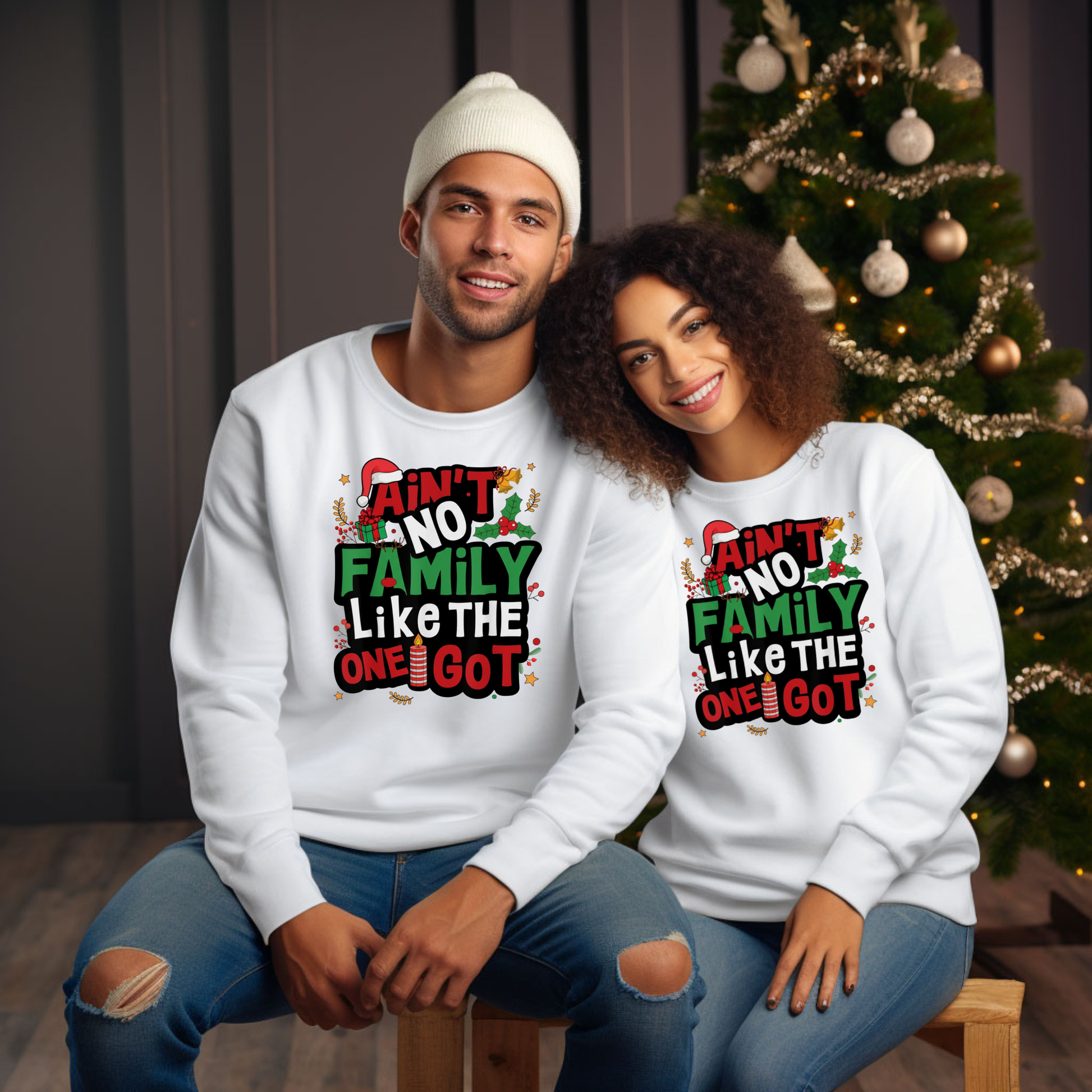 Two people wearing matching sweatshirts with a Christmas-themed design in front of a decorated Christmas tree.