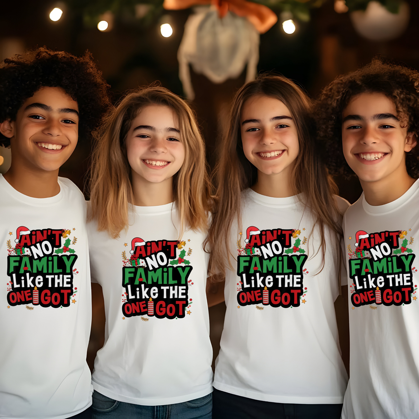 Four children wearing white t-shirts with a Christmas-themed design, standing in front of a decorated Christmas tree.