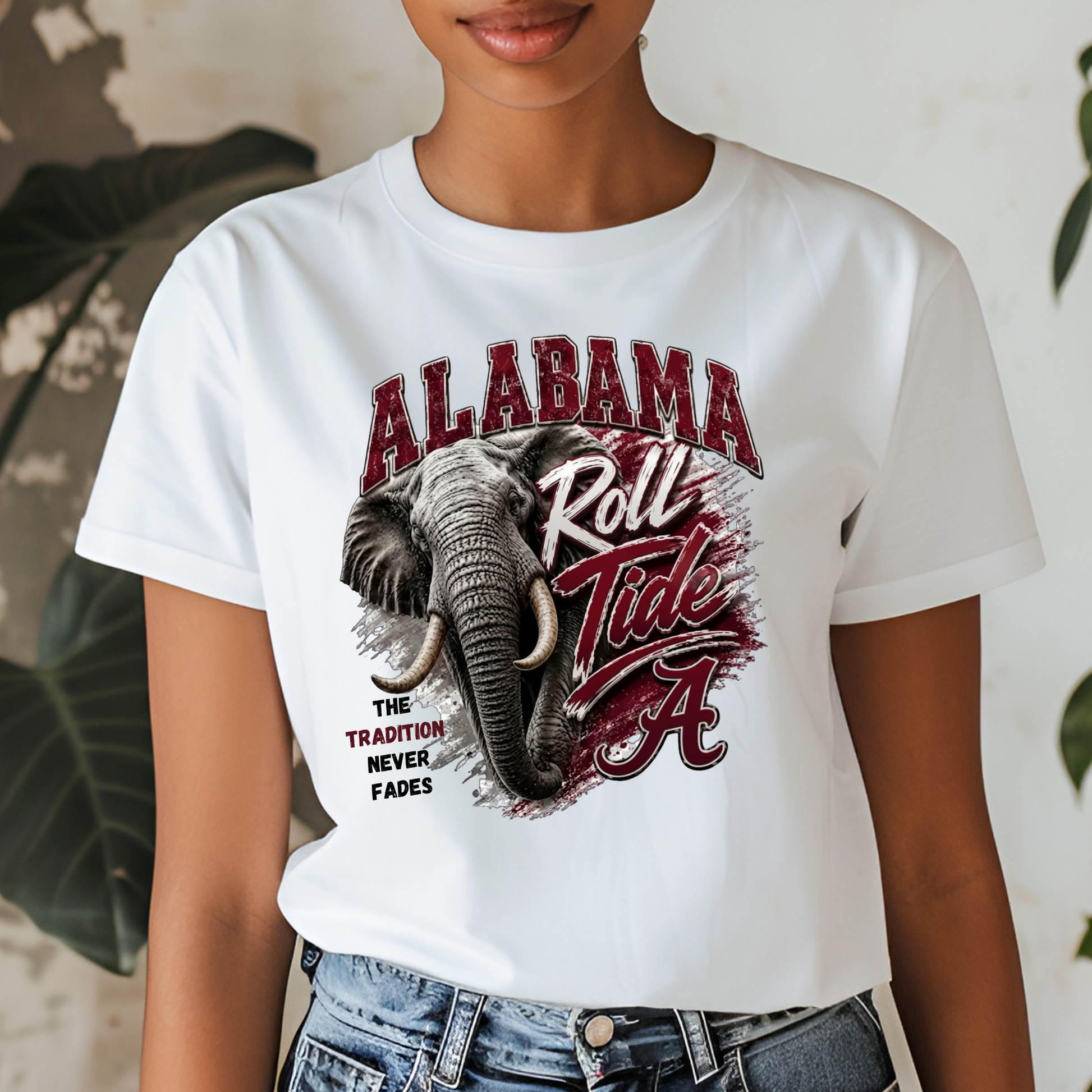 A woman wearing a white graphic t-shirt featuring an elephant and the text 'ALABAMA Roll Tide' in red and black, paired with blue jeans.