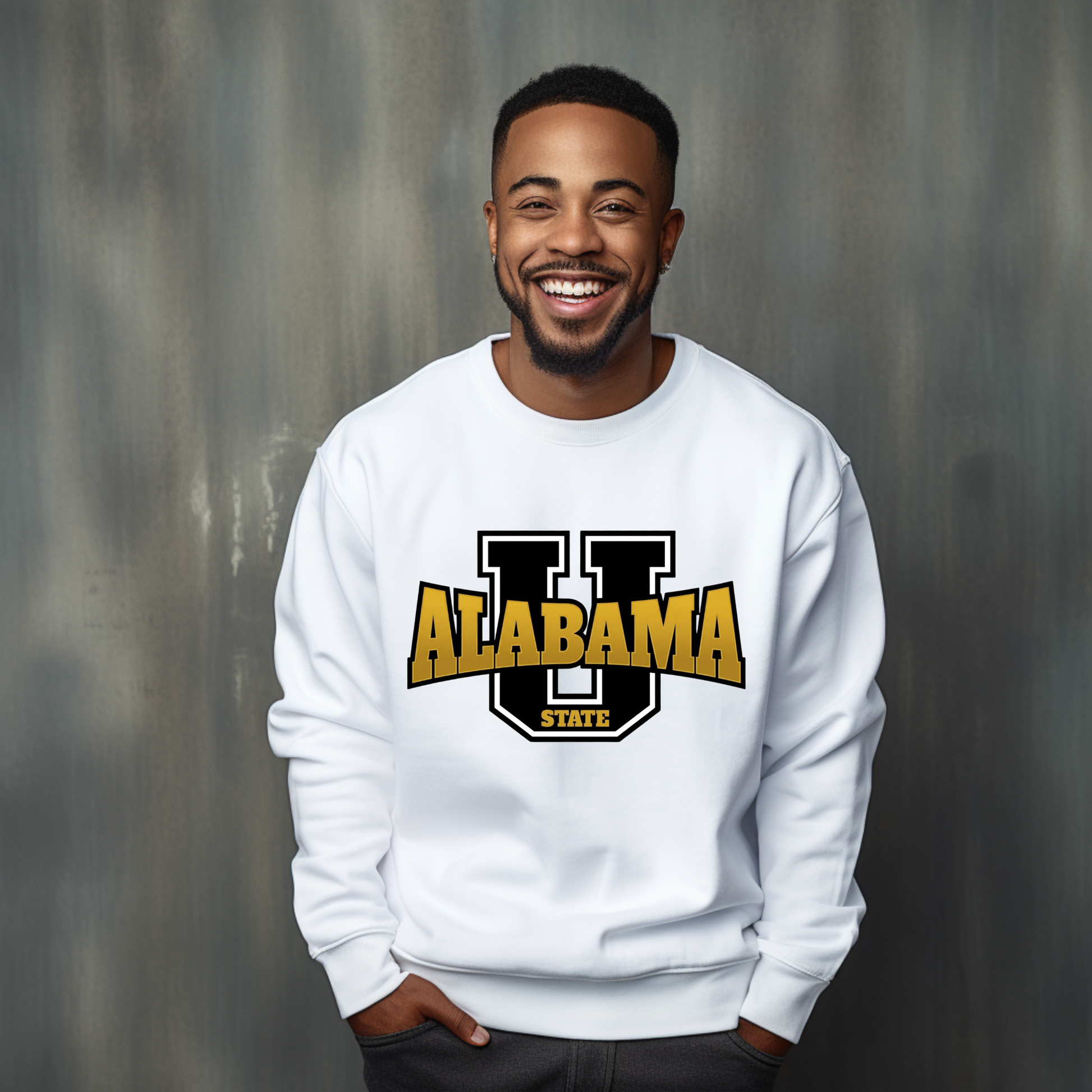 A smiling man wearing a white crewneck sweatshirt with a large 'U ALABAMA STATE' graphic in black and gold on the chest, standing against a textured gray background.