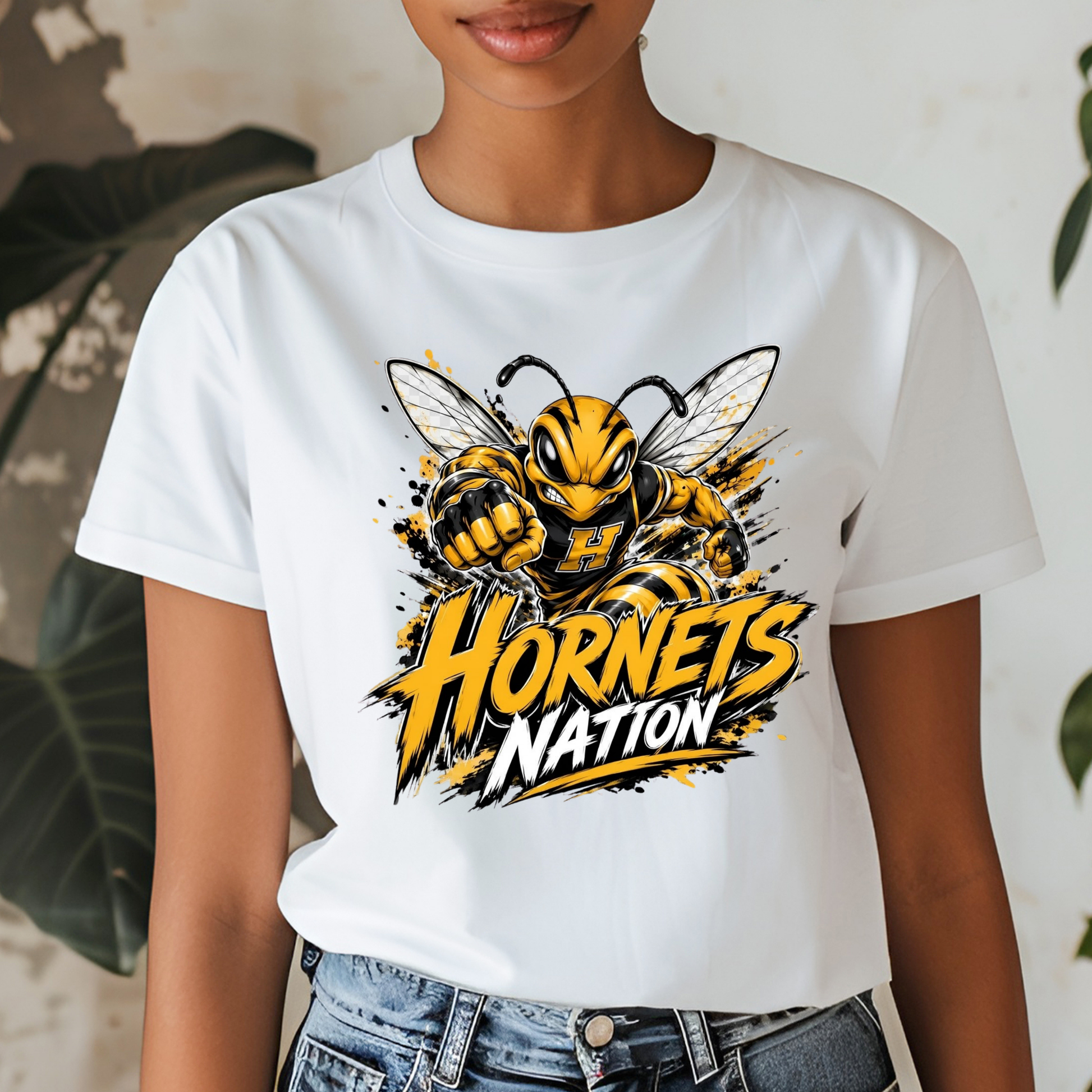 A white short-sleeve graphic t-shirt featuring a cartoon hornet mascot and the text 'Hornets Nation' in yellow and black, worn by a model with blue jeans.