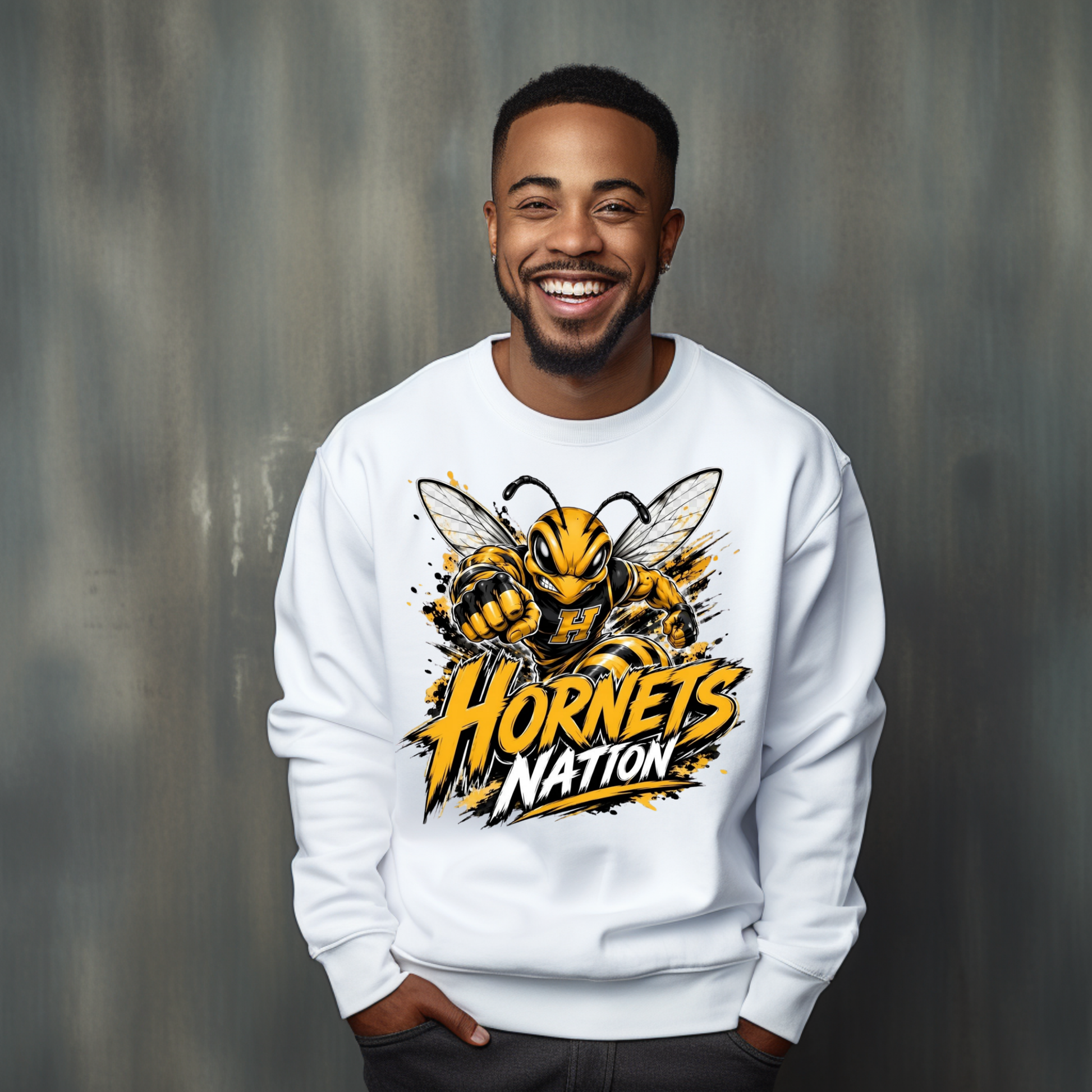 A smiling man wearing a white crewneck sweatshirt with a large yellow and black hornet graphic and the words 'Hornets Nation' on the front, posed against a textured gray studio background.