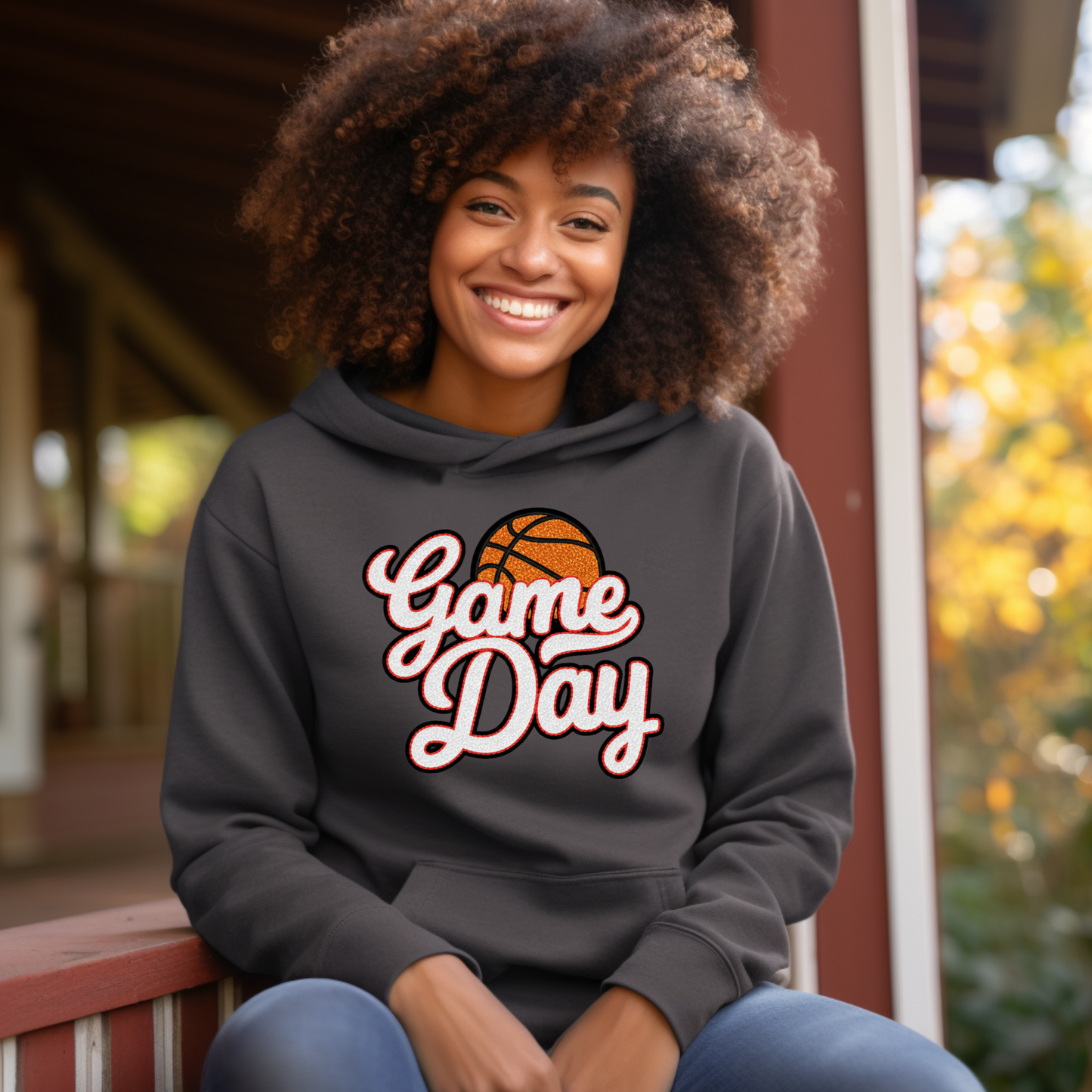 Person wearing a 'Game Day' hoodie with a basketball graphic, sitting outdoors.