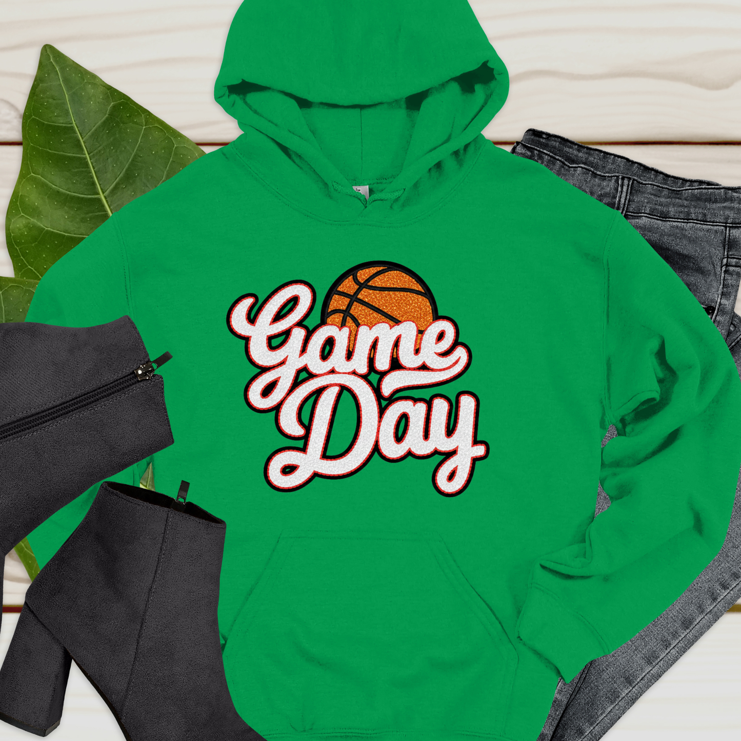 Green hoodie with 'Game Day' and basketball graphic on a light wooden surface.