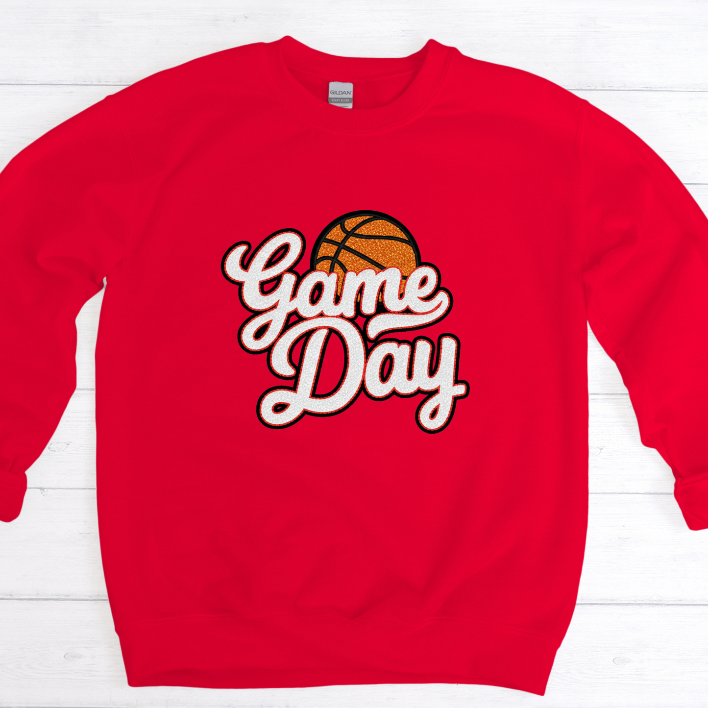 Red sweatshirt with 'Game Day' and basketball graphic on a white wooden background