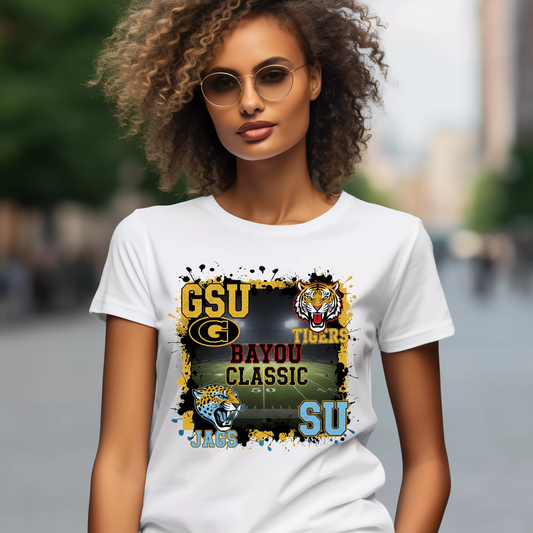 Woman wearing a white t-shirt with sports team graphics and text. Bayou Classic Football T-Shirt - Grambling State GSU Tigers vs. Southern University SU Jags Tee