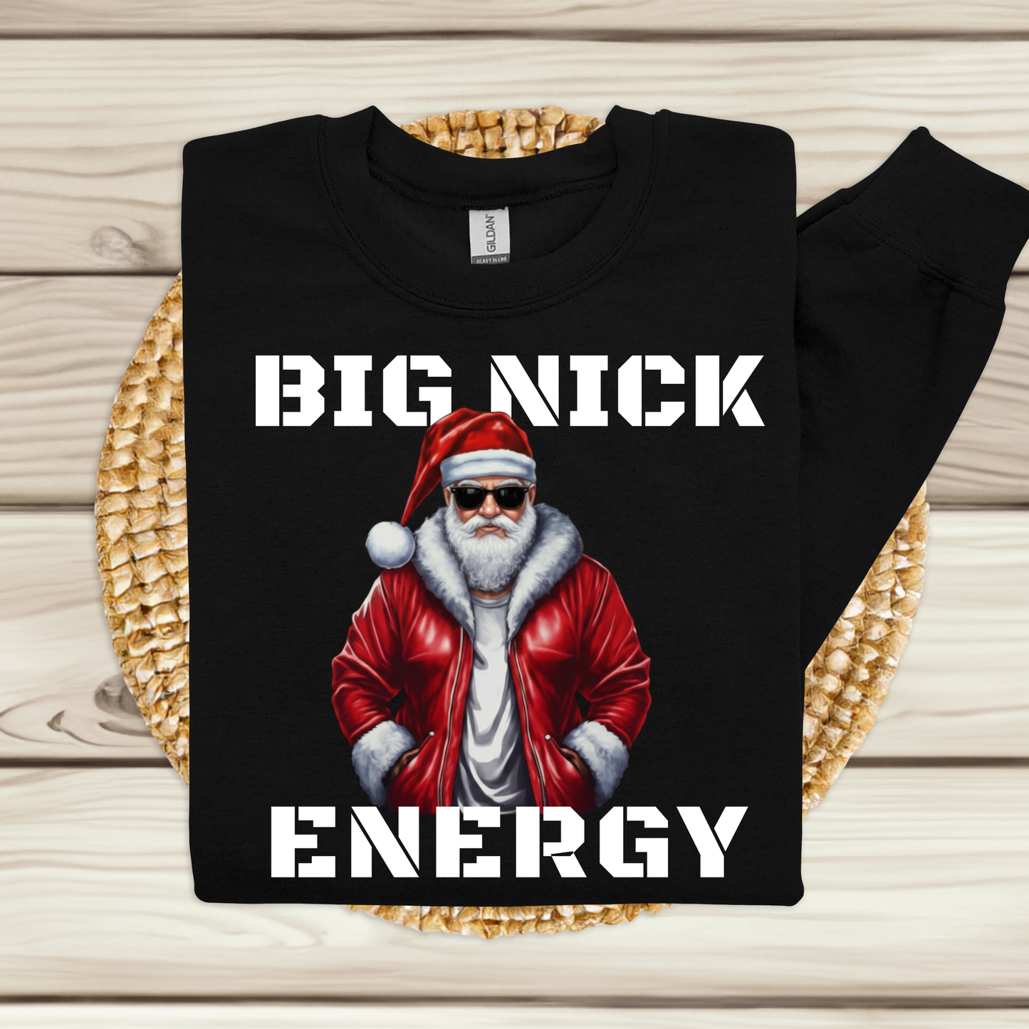 Black sweatshirt with Santa Claus graphic and 'BIG NICK ENERGY' text on a wooden surface