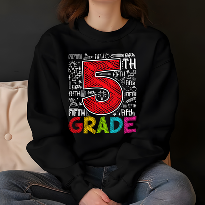 A person wearing a black sweatshirt with a colorful '5th Grade' graphic, sitting in front of a dark background.