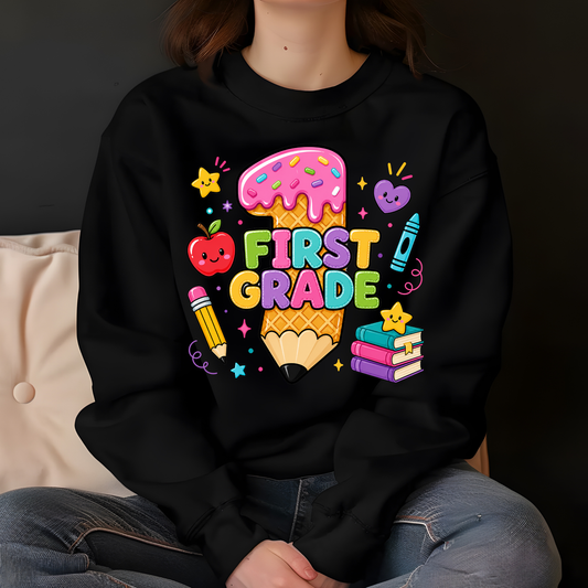 A person wearing a black crewneck sweatshirt with a colorful 'First Grade' graphic on the chest, paired with blue jeans, sitting against a dark background.