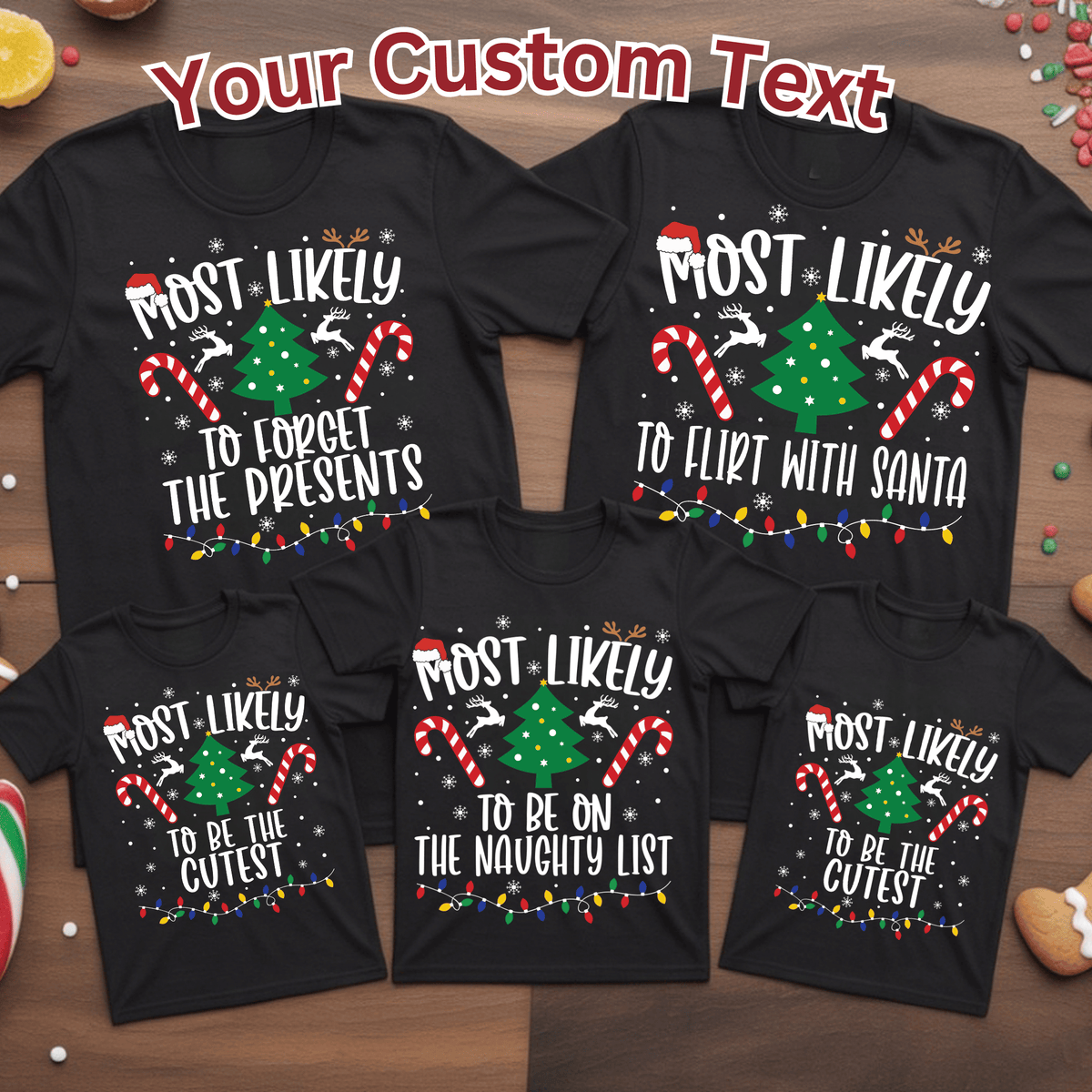 Five black Christmas-themed T-shirts shown in a flat-lay arrangement on a wooden surface, each with a different printed holiday phrase in white text. The shirts feature festive graphics including candy canes, a green Christmas tree, reindeer, snowflakes, and multicolored string lights.