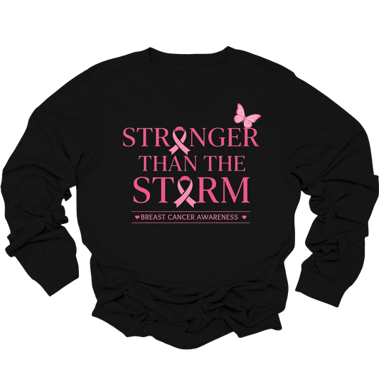 A black long-sleeve crewneck sweatshirt featuring a pink graphic print on the front that reads 'STRONGER THAN THE STORM' with a pink ribbon and butterfly, and 'BREAST CANCER AWARENESS' underneath.