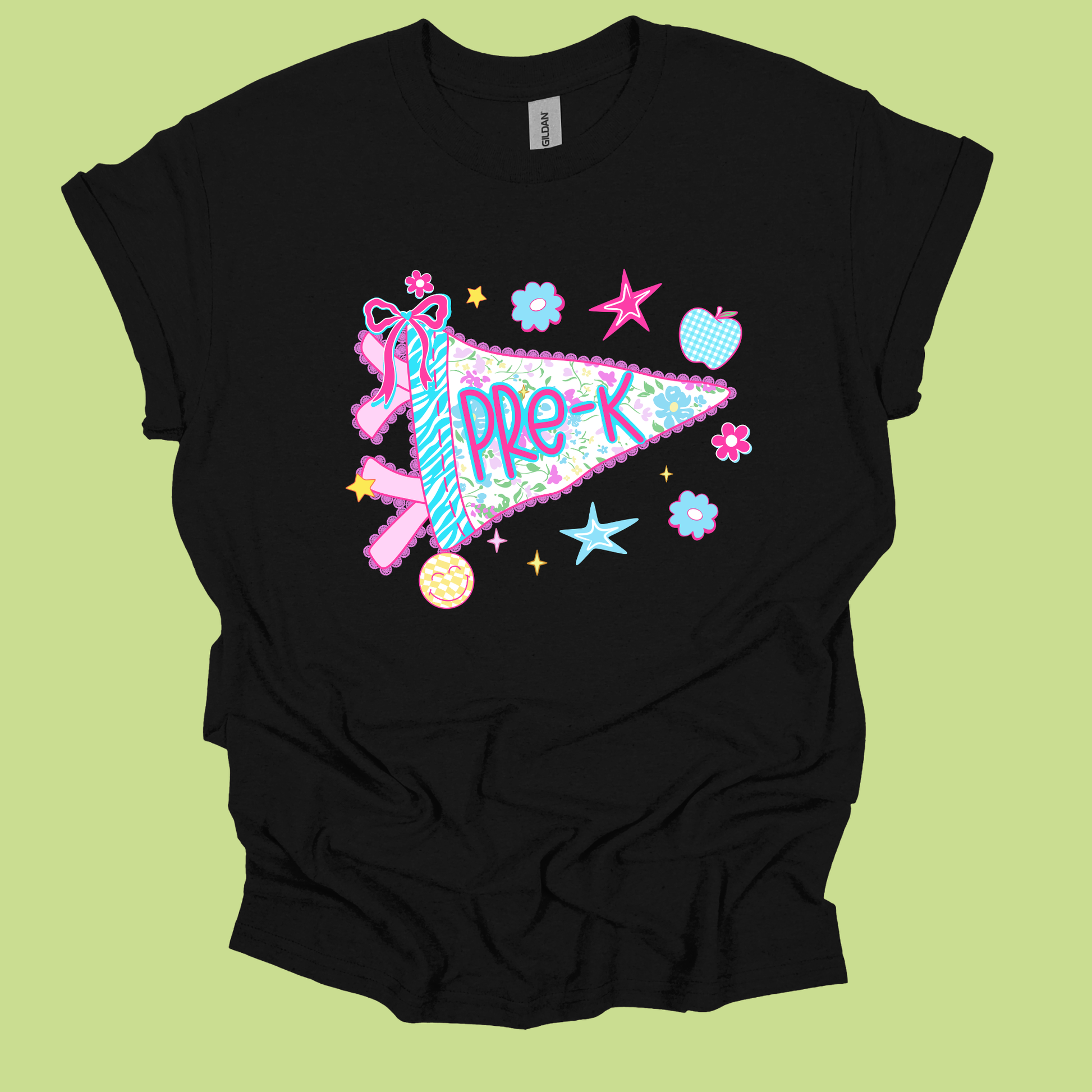 A black short-sleeve t-shirt with a colorful graphic of a pink and blue pennant reading 'PRE-K' surrounded by stars, flowers, and a ribbon, displayed on a light green background.
