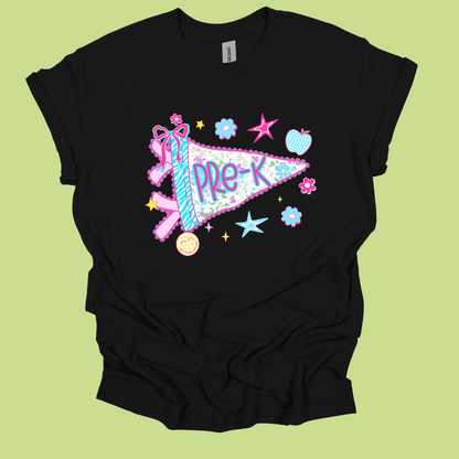 A black short-sleeve t-shirt with a colorful graphic of a pink and blue pennant reading 'PRE-K' surrounded by stars, flowers, and a ribbon, displayed on a light green background.