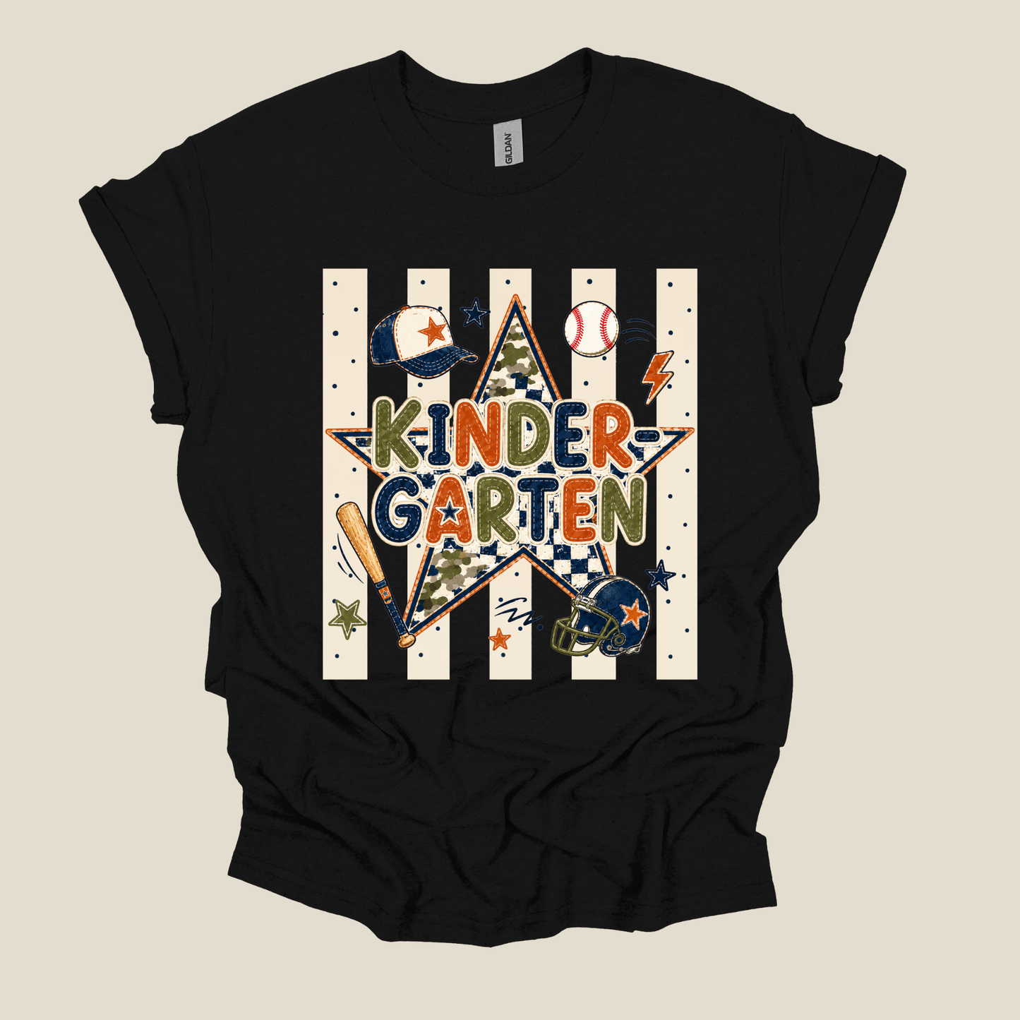 A black short-sleeve t-shirt with a colorful graphic on the front that reads 'KINDER GARTEN' inside a star, surrounded by baseball-themed illustrations like a baseball, bat, helmet, and lightning bolt, set against a background of vertical white stripes.