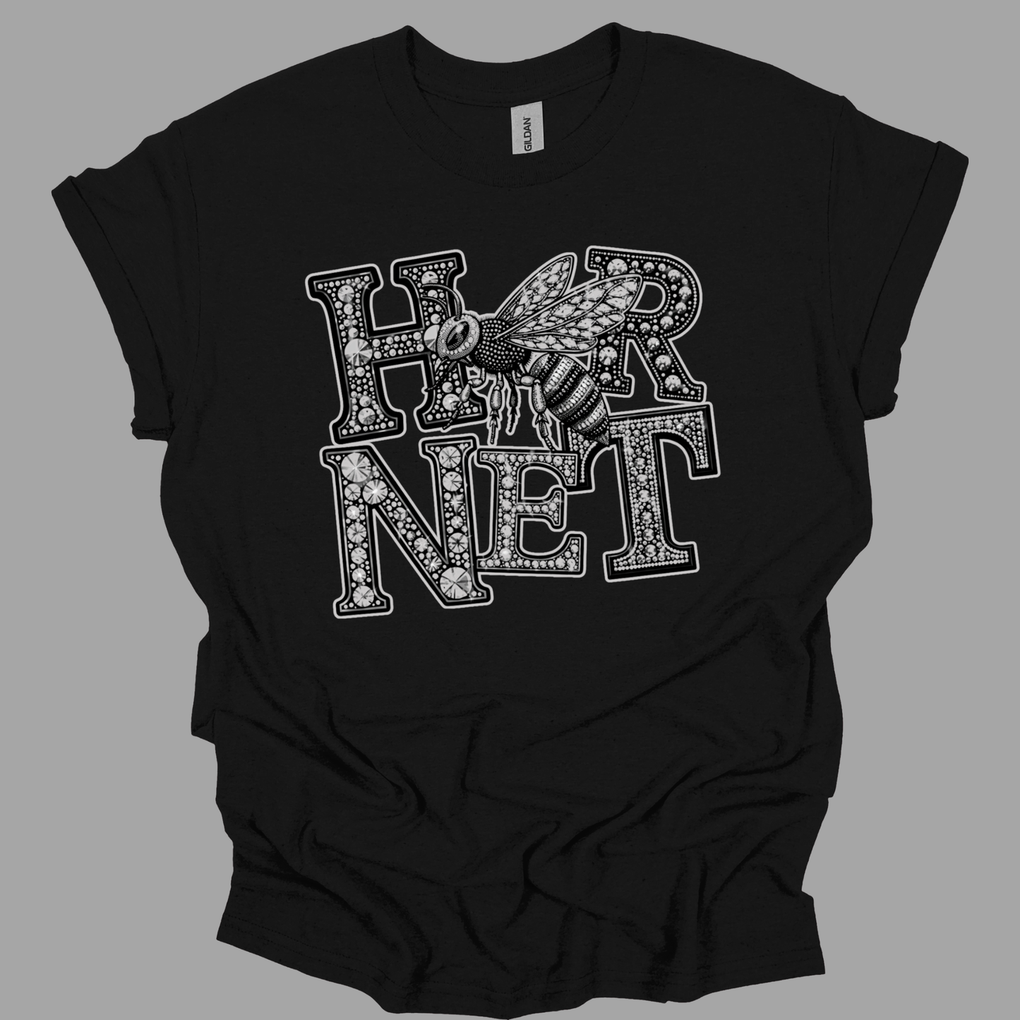 A black short-sleeve t-shirt with a graphic print of the word 'HARNESS' in a dotted, floral pattern, overlaid with an illustration of a bee. The shirt is displayed flat against a solid gray background.